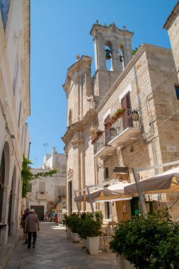 Polignano a Mare, İtalya. 03 07 2019. Polignano 'nun tarihi merkezinde Purgatorio Rectoral Kilisesi. Turistlerin bar terasları ve evler arasında yürüdüğü dar sokaklar.