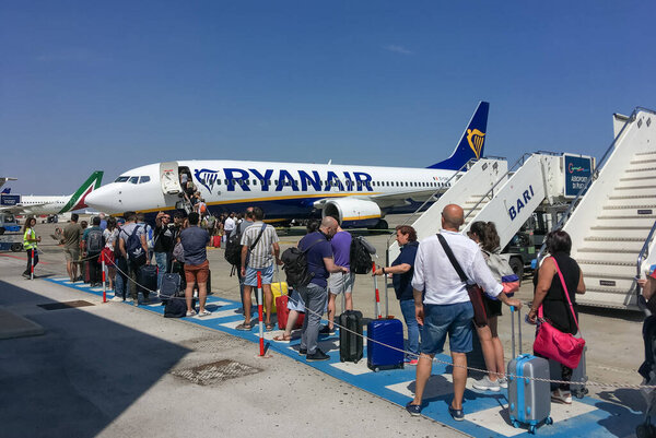 Bari, Italy. 07 04 2019. Exterior of the Bari-Palese airport, Aeroporto Internazionale di Bari-Karol Wojtyla. Travelers waiting in a queue to board a Ryanair plane.