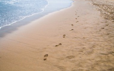 Nazik dalgalardan sonra taze ayak izleri. Los Genoveses sahilinde yaz günü, San Jose, Almerya, İspanya. Cabo de Gata Doğal Parkı.