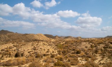 Tabernas, Almeria, İspanya civarındaki çöl manzarası. Tepelerden ve küçük bitki örtüsü olan derin vadilerden oluşan çorak bir arazi. Bulutlu yaz günü.
