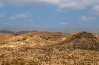 Tabernas, Almeria, İspanya civarındaki çöl manzarası. Tepelerden ve küçük bitki örtüsü olan derin vadilerden oluşan çorak bir arazi. Bulutlu yaz günü.