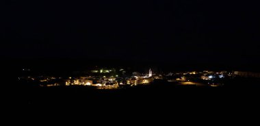 Şehrin gece panoramik görüntüsü, El Granado, Huelva, Endülüs, İspanya. Şehir sokakları, merkezde kilise çan kulesi olan belediyenin sokak lambalarıyla aydınlanıyor..