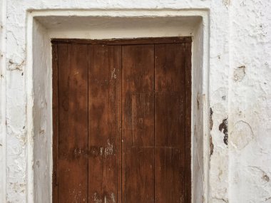 İspanya 'nın Sanlucar de Guadiana şehrinde beyazlatılmış bir duvarda tahta bir kapı. Eski ve ıssız bir evin kapalı ve boyalı kahverengi penceresi.