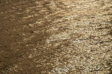 Su yüzeyi dalgalarında altın parıltı. Günbatımında güneş ışığının yansıması Sanlucar de Guadiana 'daki Guadiana Nehri' nin sularında, Huelva, İspanya.