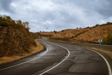 Paved road with curves and wet from the recent autumn rain. Rural road HU-4401 at km 14 on a rainy day in Sanlucar de Guadiana, Andalusia, Spain. clipart