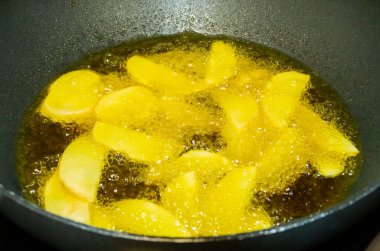 Sıcak yağda kızaran patateslerin yakın çekimi. Patates parçaları hazırlanırken kaynayan yağın kabarcıklarıyla çevrili. Patates kızartması.