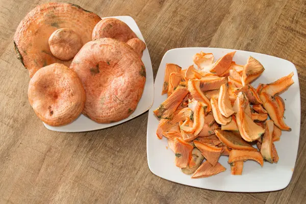 stock image Dishes of fresh and washed mushrooms. Plates with whole mushrooms and with chopped mushrooms. Dish of Lactarius deliciosus, delicious milk cap, saffron milk cap or red pine mushroom ready to be cooked. Madrid, Spain.