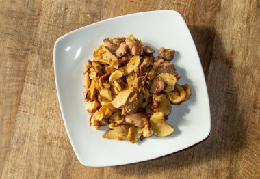 Porcini ile karıştırılmış hindi ve beyaz tabakta soğan. Sotelenmiş hindi eti, domuz eti, soğan ve zeytinyağında pişirilmiş badem..