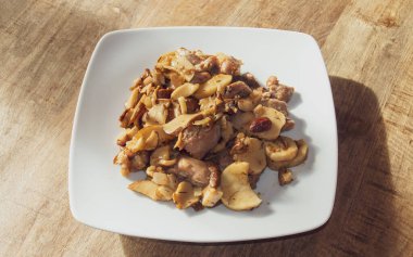 Porcini ile karıştırılmış hindi ve beyaz tabakta soğan. Sotelenmiş hindi eti, domuz eti, soğan ve zeytinyağında pişirilmiş badem..