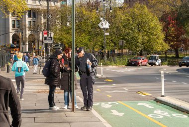 New York, ABD. 11 09 2019. Polis Manhattan 'daki Park Row' da iki turiste yardım ediyor. Belediye binasının yanındaki kaldırımda yürüyen insanların olduğu şehir manzarası..