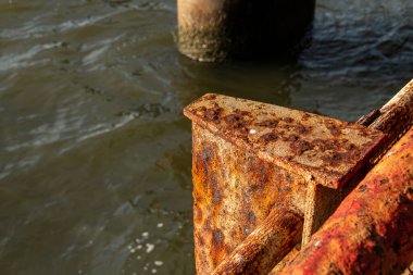 Rusty metal pillar on the bank of the East River in New York, USA. Metal beam on the river bank affected by sea spray from brackish water in the bay on Manhattan Island. clipart