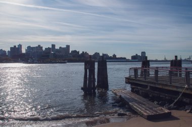 New York, ABD 'deki East River kıyısındaki sularda tahta sütunlar. Brooklyn Köprüsü 'nün yanındaki Manhattan' dan Brooklyn rıhtım binaları. NYC, 2019.