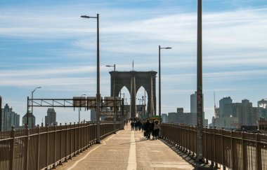 New York, ABD 'de Brooklyn Köprüsü' nü geçen insanlar. Soğuk bir sonbahar sabahında şehir manzarası. Arkaplanda Brooklyn 'in doğu nehrinin kıyısındaki binaları var. 2019.