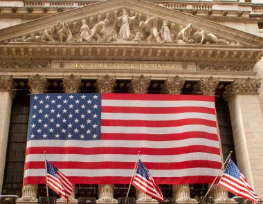Wall Street 'teki New York Borsası' nda sergilenen Amerikan bayrağının yakın çekimi. Giriş timpanumunu destekleyen sütunların üzerine bayrak gerildi.