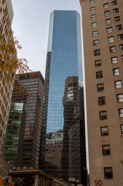 New York, ABD. 11 09 2019. New York gökdeleninin bir başkasının camına yansıması. Manhattan, Whitehall Caddesi 33 numaradaki Broad Financial Center emlak yönetim şirketi..