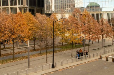 New York, ABD. 11 09 2019. New York 'taki Dünya Ticaret Merkezi' ndeki Sıfır Noktası parkının sonbahar manzarası. Liberty Caddesi boyunca rehberi takip eden bir grup turist.