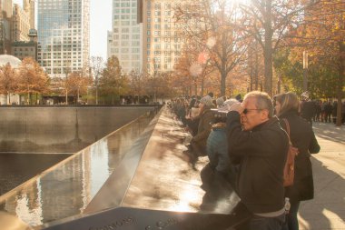 New York, ABD. 11 09 2019. Dünya Ticaret Merkezi Anma Pınarı 'ndaki turistler. Sıfır noktasındaki kule havuzu. 11 Eylül Anıtı İkiz Kuleler 'de. Ön planda fotoğrafçı.