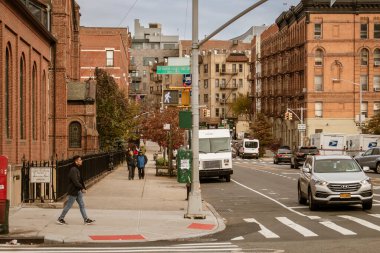 New York, ABD. 11 10 2019. Harlem mahallesinde kaldırımda yürüyen insanlar. Morningside Bulvarı 'ndan yaya geçidi Kutsal Aile Kilisesi' nin yanındaki Aziz Joseph Kilisesi 'ne..