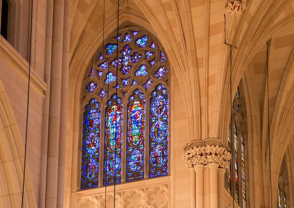 New York, ABD 'deki St. Patrick Katedrali' nin içi. Beşinci Cadde 'deki katedralin aydınlatılmış Gotik mimari detayları. Lekeli cam pencere içeriden.
