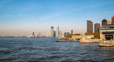 New York, ABD 'de Manhattan' ın finans bölgesinin güneyindeki tahta iskeleli. Arka planda, New Jersey gökdelenlerinin panoramik görüntüsü Yukarı Körfez ve Hudson Nehri 'nin suları boyunca uzanır..