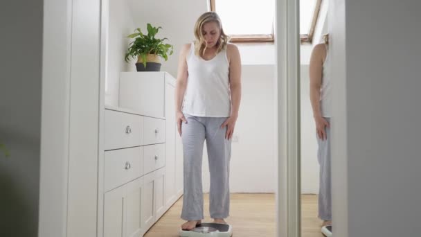 Reife Frau Den Wechseljahren Besorgt Über Gewichtszunahme Auf Waage Schlafzimmer — Stockvideo