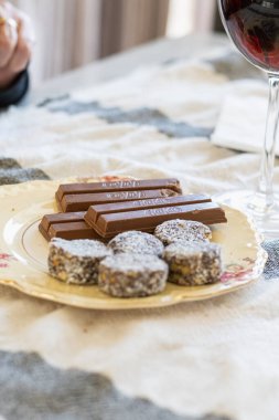 Tabakta geleneksel çikolatalı kurabiyeler ve masada bir bardak şarap.