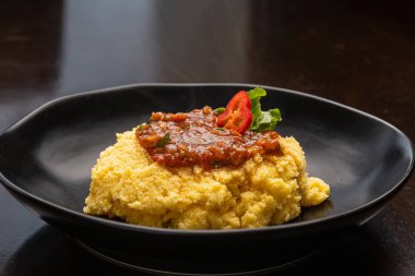 Domates soslu siyah tabak ve erimiş peynir unu.