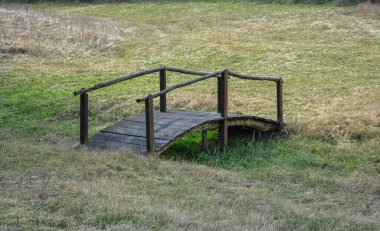 Küçük kuru bir kanalın üzerinde küçük tahta bir köprü. Kuru deresi olan yeşil bir düzlükte ahşap köprü..