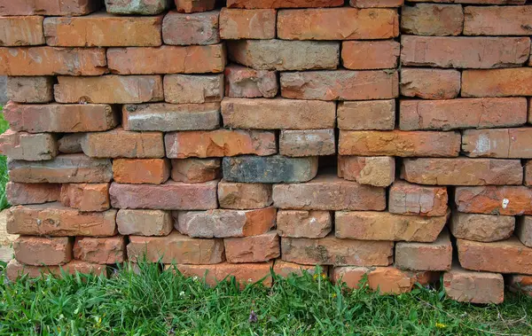 used red bricks are stacked on green grass. concept of reusing building material.