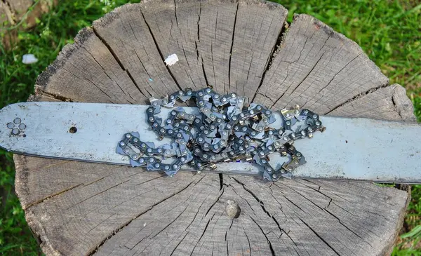 old tire and chainsaw chain on a wooden stump. chainsaw parts.