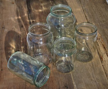 Güneşten parlayan cam kavanozlar. Eski ahşap bir masada farklı boyutlarda cam kavanozlar muhafaza edilir..