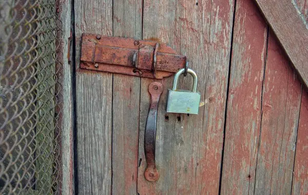 Kapıda paslı bir kilit var. Eski ahşap kapıya asma kilit takılmış.