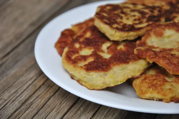 Ekşi kremalı kızarmış gözleme ve beyaz ahşap arka planda bir tabak Rus mutfağı.