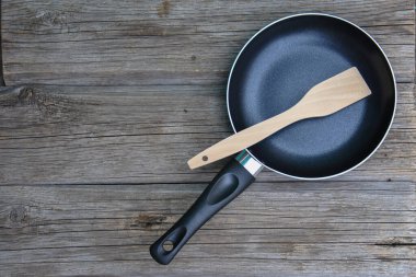 Ahşap arka planda ahşap mutfak spatulası ve kızartma tavası.