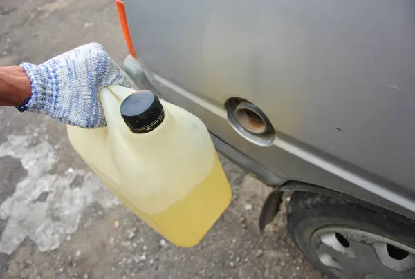 Elinde yakıt olan plastik bir kutu.