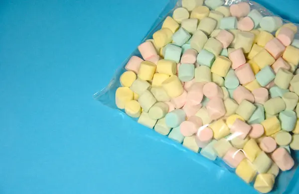 mavi arkaplanda ambalajda renkli marşmelovlar