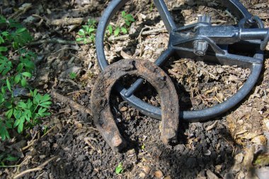 Metal dedektörünün bulduğu paslı at nalı. Paslı at nalı ve metal dedektör bobini. Metal dedektör arama kavramı