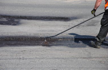 Çukur onarımından önce asfalt yolu işleniyor. Yol kenarında asfalt yolun tamiri