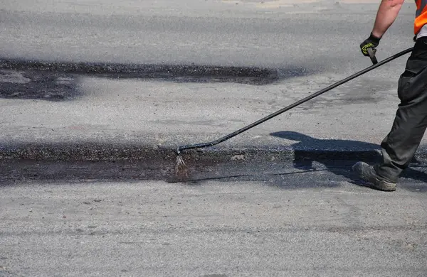 Çukur onarımından önce asfalt yolu işleniyor. Yol kenarında asfalt yolun tamiri