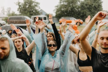06.08.2022 Irpin, Ukraine: a group of people dancing in the rain wearing raincoats and enjoying a live performance by artists