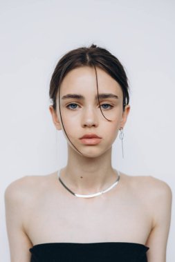 Geniş bir fotoğraf stüdyosunda doğal ışık saçan 15 yaşındaki genç bir kızın şık portresi.