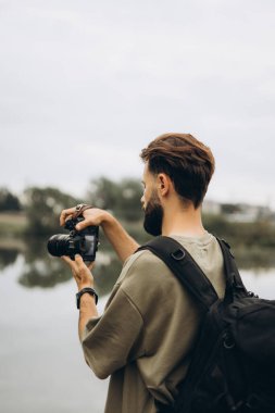 Elinde modern bir SLR kamerası olan genç bir adam.