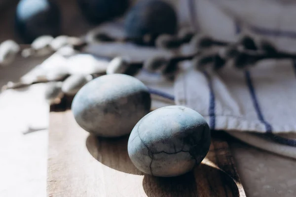 Stock image Stylish easter eggs in rustic nest or desk on table. Natural dyed colorful easter eggs with feathers on rural textile background. Happy Easter.