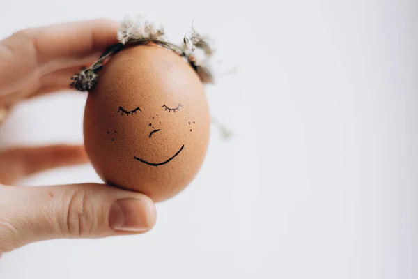 stock image Painted Easter eggs with natural coloring and drawings in the form of emotions. The fingers of a girl's hand hold an Easter egg