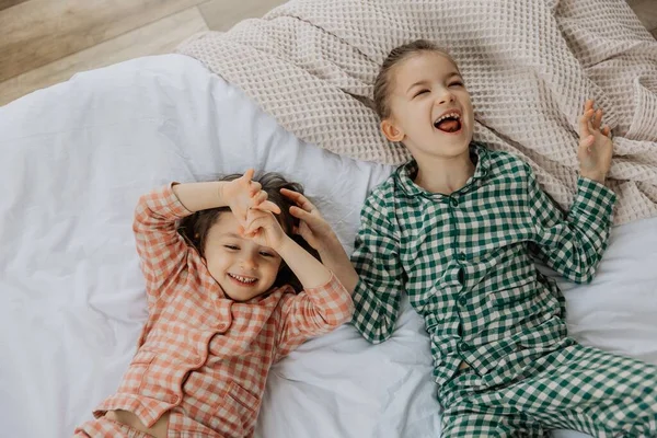 Günaydın çocuklar, en iyi manzara. Mutlu kız kardeşler bir yatakta yatıyor. Sabah uyanan küçük kızlar bir yatakta. 