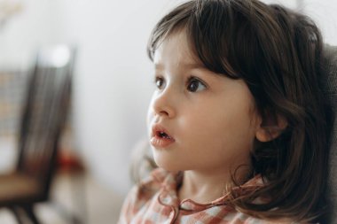 Önüne odaklanmış küçük bir kızın yan portresi.