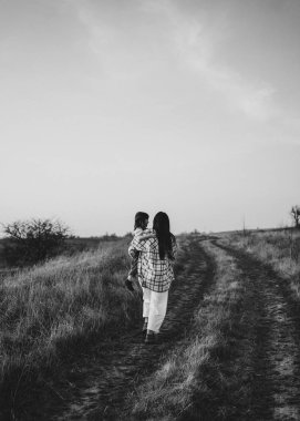 Nehrin kenarında duran şık, klasik bir aile, bir çocuk tutuyor, sakin, doğal bir ortamda, siyah-beyaz yakalanmış.