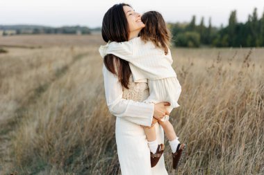 Bir anne ve çocuğun portresi. Akşamları doğal bir arka planda sarılıyorlar.