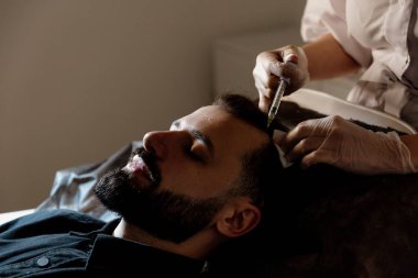 Çekici bir adam klinikte saç dökülmesini tedavi etmek için mezoterapi iğnesi olur. Deriye ve kafa derisine enjeksiyon.