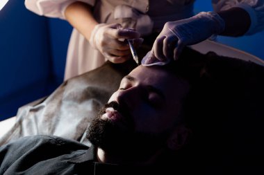 Çekici bir adam klinikte saç dökülmesini tedavi etmek için mezoterapi iğnesi olur. Deriye ve kafa derisine enjeksiyon.